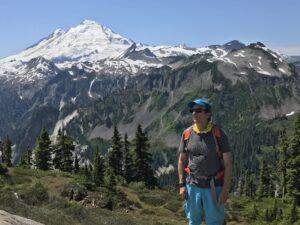 A man standing on top of a mountain with trees.